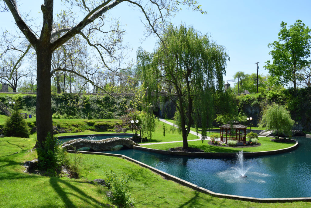 Street-level view overlooking Sunken Gardens, revealing the lush vegetation and walking paths within the former limestone quarry.