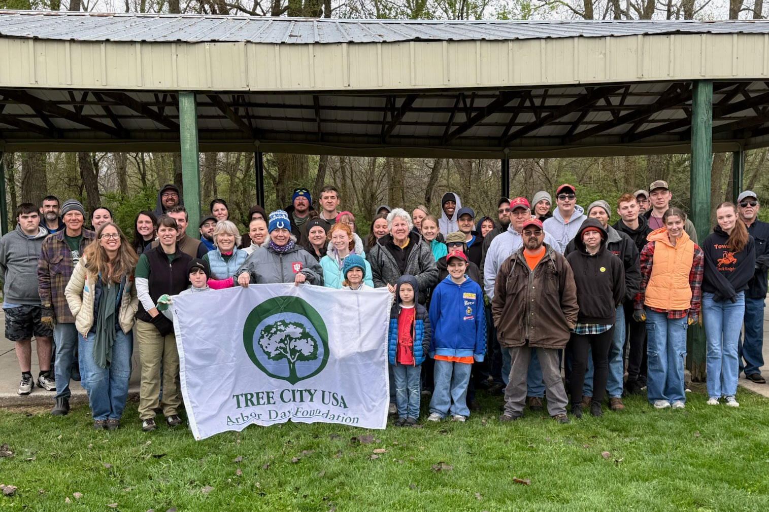 A group of volunteers on Arbor Day presenting a Tree City USA banner.