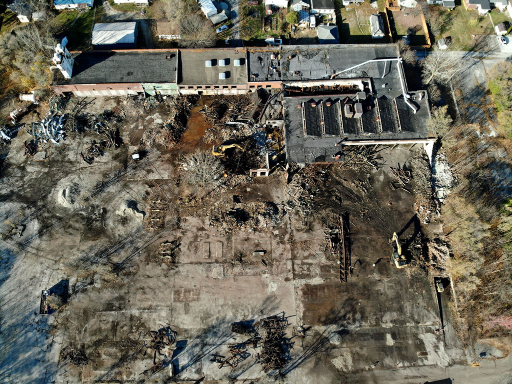 Aerial photograph showing demolition progress at the HK Porter industrial site in Huntington, Indiana, with cleared structures and active work areas visible.